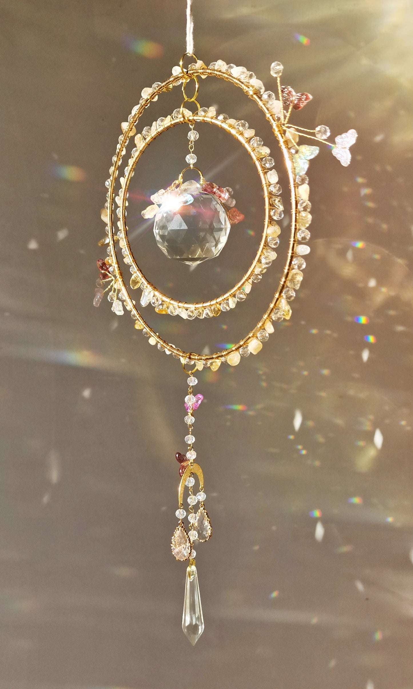 DIY crystal suncatcher in progress, with hands assembling butterfly beads and wire onto a hoop